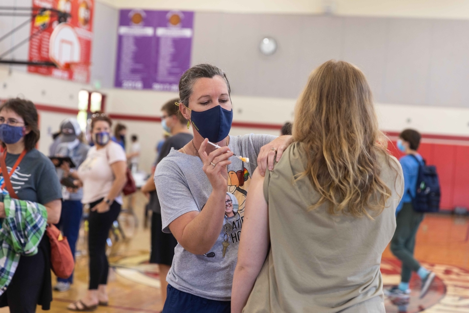 A woman vaccinates another woman in the arm