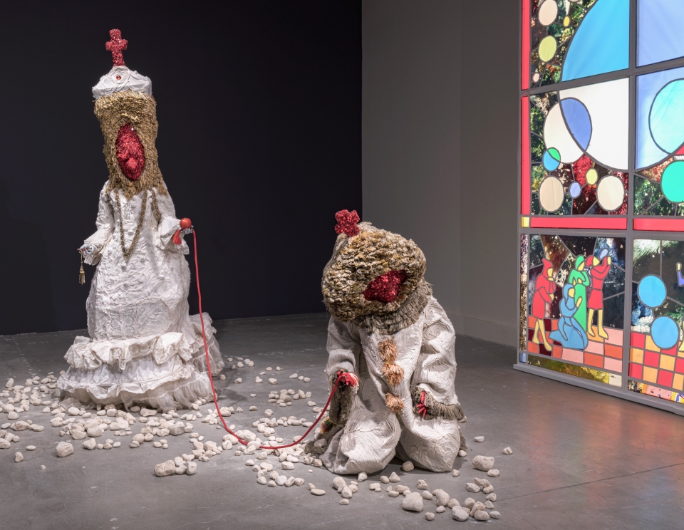 Sculptures in exhibit with white costumes and orange faces