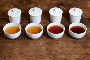 Four glasses of tea ranging from light orange to a deep red