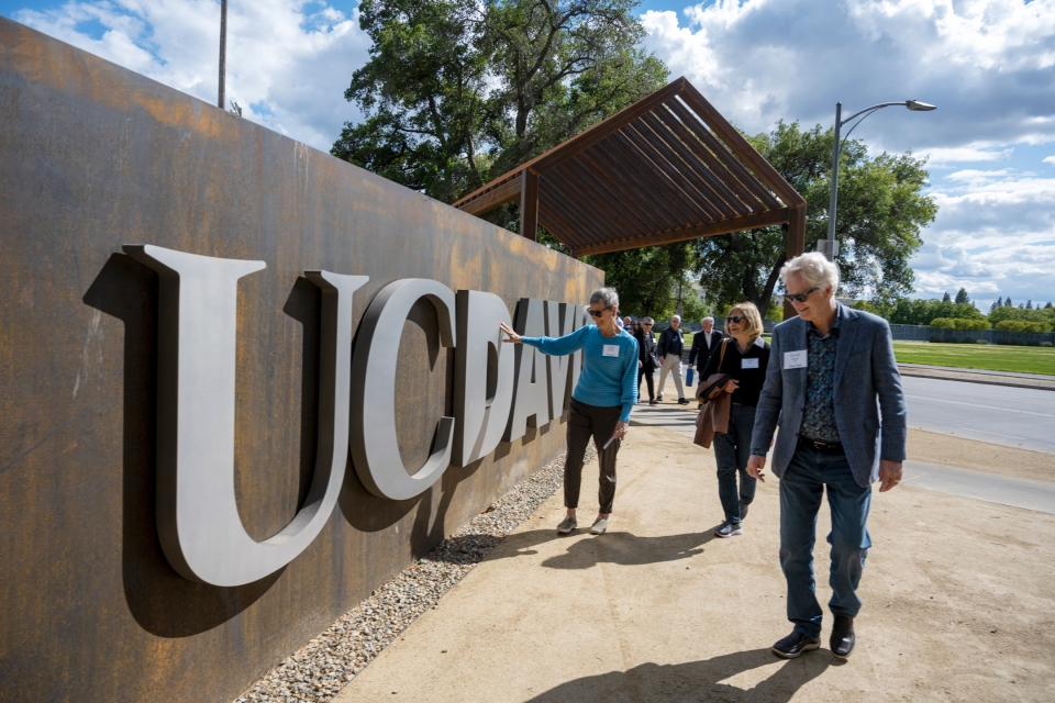 Class of 1968 alumni walk by and touch the new gateway structure on campus.