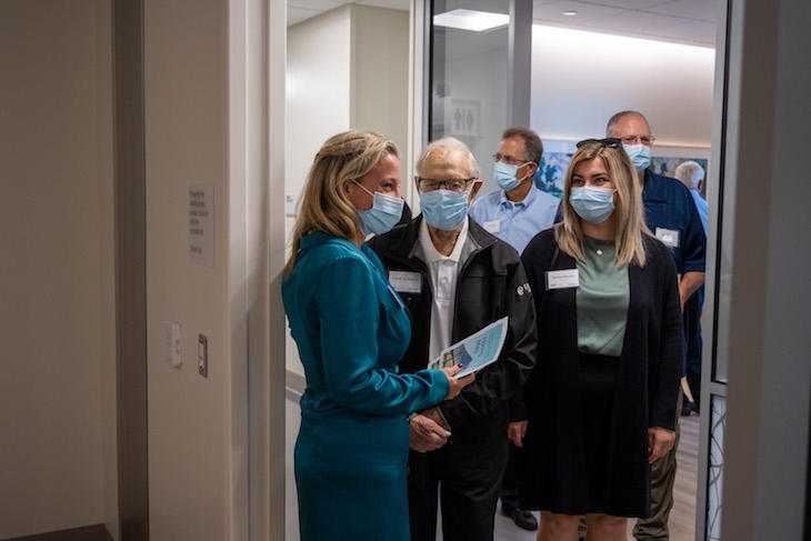 A group of five people wearing masks stand at the entrance to a room. 