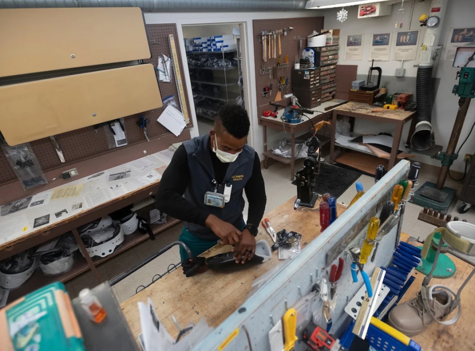 man adjusting a prosthetic hand at a workshop table