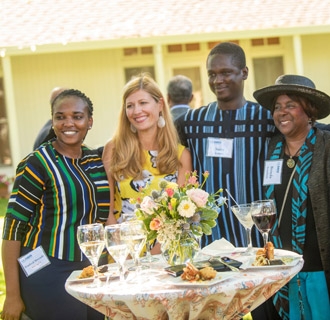 A group of Mandela Washington fellows pose behind a decorated cocktail table on the lawn.