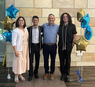 Sergio Maciel and Pablo Reguerin flanked by UC Davis staff members in between mylar balloon decorations in the shape of stars.