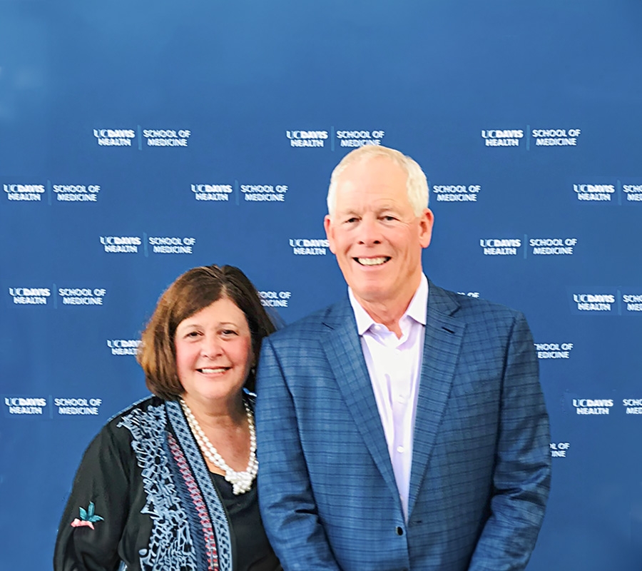 Lydia Howell and her husband pose in front of a blue backdrop.